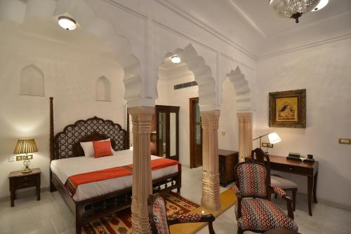 a bedroom with a bed and a desk and chairs at Haveli Dharampura & Golden Haveli- UNESCO awarded Boutique Heritage Hotel in New Delhi