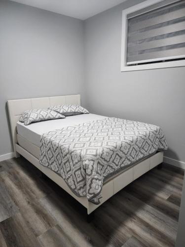 a bedroom with a bed with a white bedspread at lovely 2bed & 1 Bath Basement Suite for 4 guests in Calgary