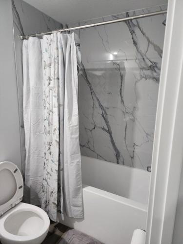 a bathroom with a white toilet and a shower at lovely 2bed & 1 Bath Basement Suite for 4 guests in Calgary