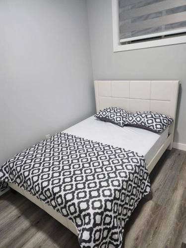 a bed with a black and white comforter and pillows at lovely 2bed & 1 Bath Basement Suite for 4 guests in Calgary