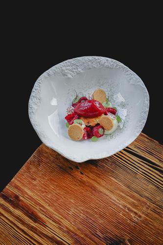 a white bowl filled with fruit on a wooden table at Auberge des Gorges - Restaurant Gastronomique & Chambres in Servoz