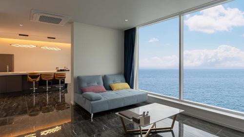 a living room with a couch and a large window at Elafonisi Poolvilla & Hotel in Gyeongju