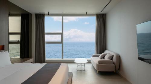 a bedroom with a bed and a couch and a large window at Elafonisi Poolvilla & Hotel in Gyeongju