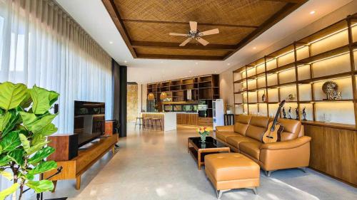 ein Wohnzimmer mit einer Couch und einem Deckenventilator in der Unterkunft Villa Brisa Tropical BMT in Buôn Kao