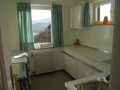eine Küche mit grünen Vorhängen, einem Waschbecken und einem Fenster in der Unterkunft Ferienbungalow in Seeboden