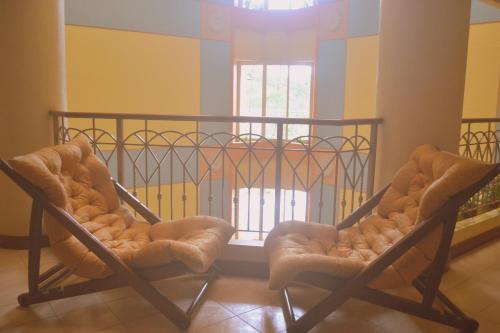 two chairs sitting in a room with a balcony at Hotel Elizabeth - Baguio in Baguio