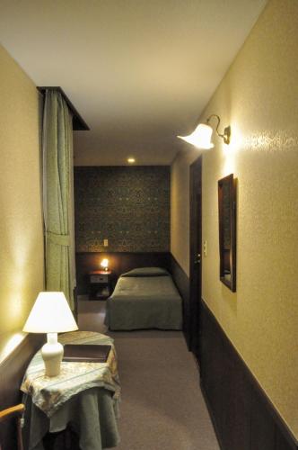 a room with two beds and a lamp on a table at Camellia Inn Yukitsubaki in Kanazawa