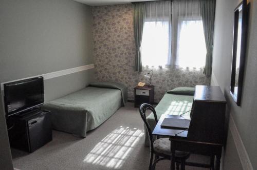 a hotel room with a bed and a desk and a table at Camellia Inn Yukitsubaki in Kanazawa