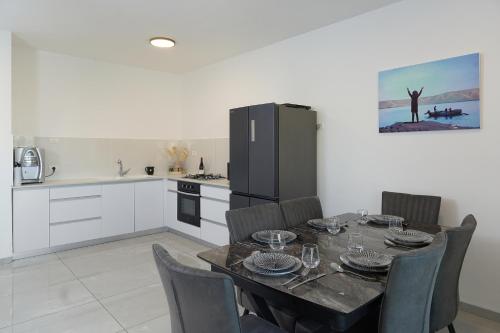 a kitchen with a table with chairs and a refrigerator at לוי-קיישן מגוון דירות גן ופנטהאוזים וסוויטות נוף ברחוב הצנחנים in Tiberias