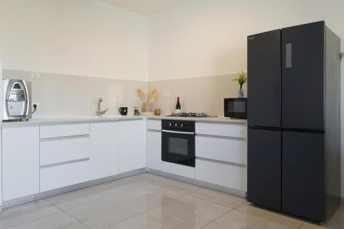 a kitchen with white cabinets and a black refrigerator at לוי-קיישן מגוון דירות גן ופנטהאוזים וסוויטות נוף ברחוב הצנחנים in Tiberias