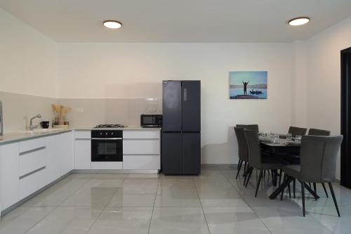 a kitchen with a black refrigerator and a table with chairs at לוי-קיישן מגוון דירות גן ופנטהאוזים וסוויטות נוף ברחוב הצנחנים in Tiberias
