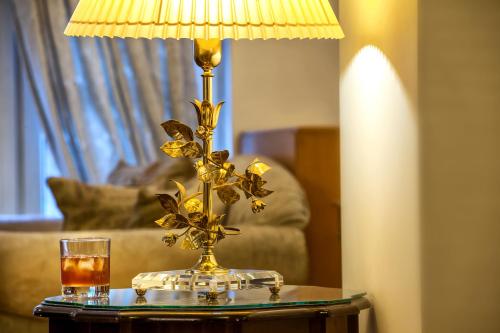 a gold lamp on a table with a drink on it at Minerva Premier Hotel in Thessaloniki