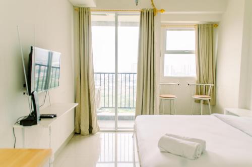 a bedroom with a bed and a tv and a balcony at Comfort and Homey Studio at Parkland Avenue Apartment By Travelio in Tangerang