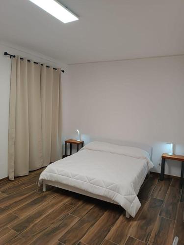 a white bedroom with a bed and wooden floors at Umberto primo rooms in Castelbuono