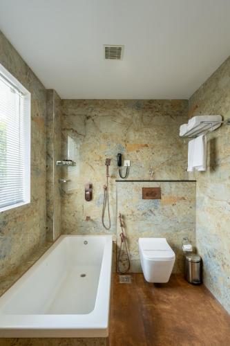 a bathroom with a bath tub and a toilet at Hybiz by Darshan in Anchal