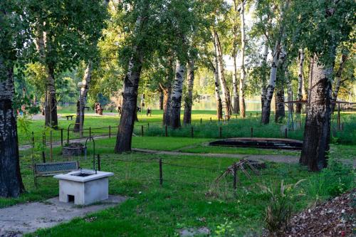 a park with trees and a white tub in the grass at Tiszavirág Apartman Màrtèly in Mártély