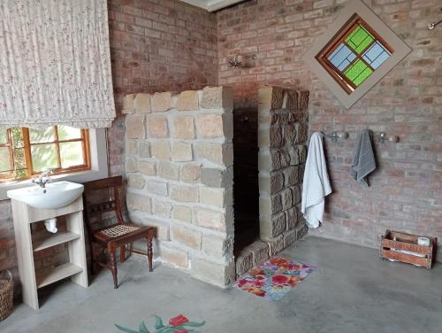 a brick bathroom with a sink and a brick wall at Studio 101 in Oudtshoorn