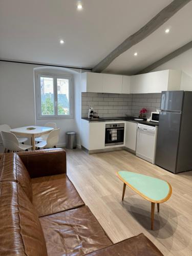 un salon avec un canapé marron et une cuisine dans l'établissement Appartement Place du Marché Bastia, à Bastia