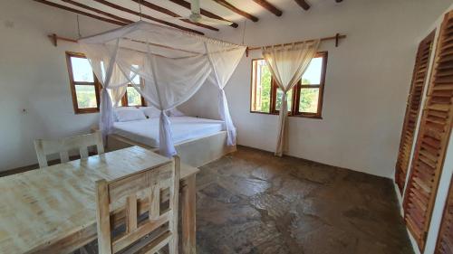 a bedroom with a bed and a table and windows at Kirepwe Ecco Camp Watamu in Watamu