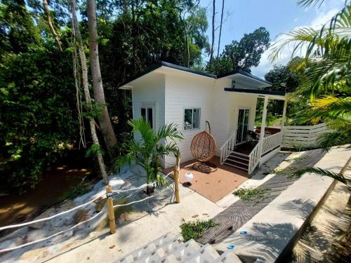 a small white house with a palm tree at Leelawadee Bungalow and Restaurant in Mae Nam