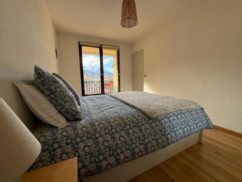 une chambre avec un grand lit et une fenêtre dans l'établissement T3 expo sud, terrasse et vue montagne à Jausiers, à Jausiers