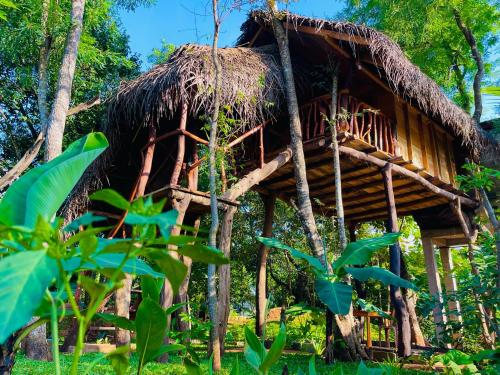 a tree house with a thatched roof at Green land tree house sigiriya in Sigiriya