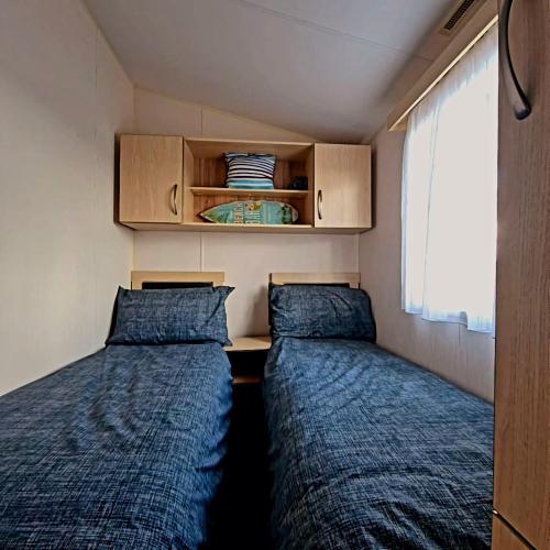 two beds in a small room with a window at Cosy Perranporth caravan, Cornwall in Perranzabuloe