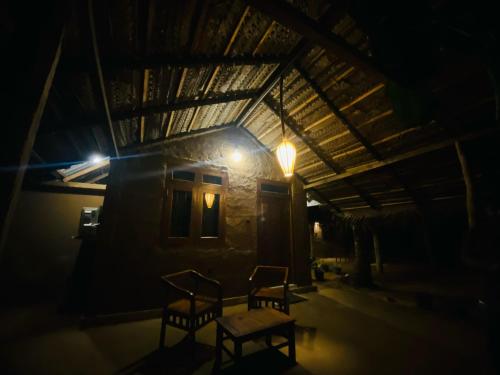 two chairs and a table in front of a house at night at Amuna Villa in Habarana