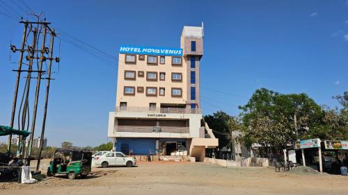 a tall building with a car parked in front of it at Hotel Nova Venus in Rajkot