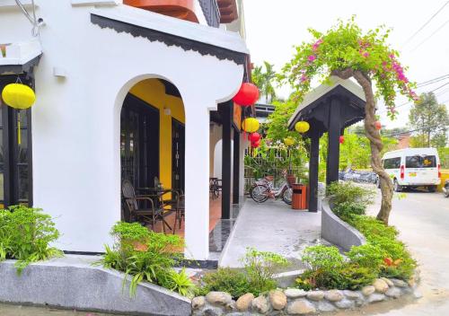 a white building with some plants and flowers at Yzistel Hoi An in Hoi An