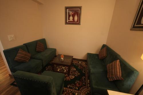 a living room with two green chairs and a table at Hotel 360 by D'Polo Dharamshala in Dharmsala