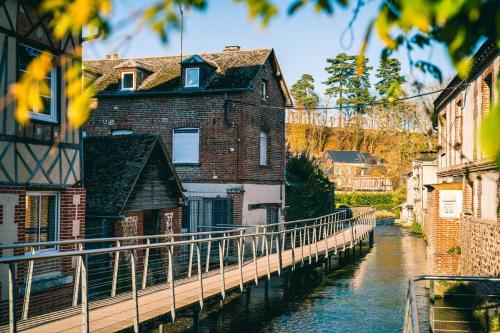 un bâtiment à côté d'une rivière avec un pont dans l'établissement Maison Normande en lisière de la forêt, à Bernay