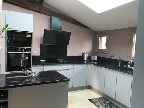 une cuisine avec des armoires blanches et des comptoirs noirs dans l'établissement Havre de paix avec piscine au cœur de la Dordogne, à Saint-Laurent-des-Hommes