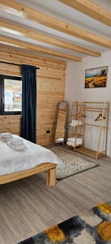 a bedroom with a bed and a wooden wall at Casuta CORE in Sadova
