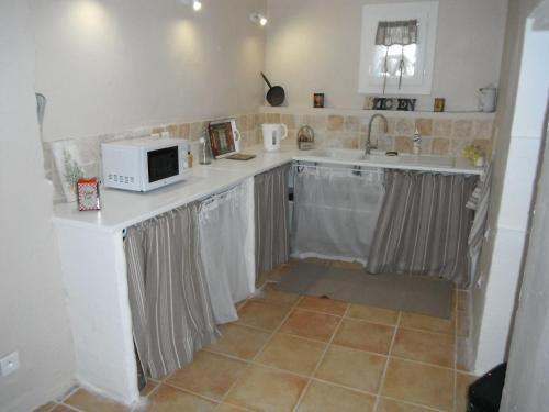 a kitchen with a sink and a microwave at Le Temps d'un Rêve in Mazan