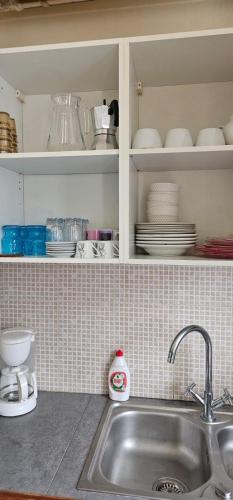 un comptoir de cuisine avec un évier et une étagère avec de la vaisselle dans l'établissement Maison proche de Paris et Aéroport Orly jusqu'à 7 personnes, à Valenton