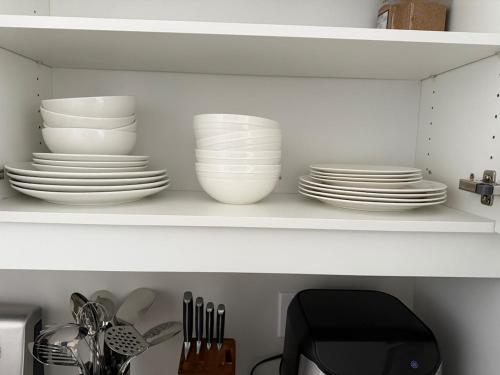 a white shelf with plates and dishes on it at Cozy 3 Bedroom Townhome Hyde Park Mall & Western University in London