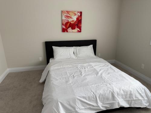a bedroom with a white bed with a black headboard at Cozy 3 Bedroom Townhome Hyde Park Mall & Western University in London