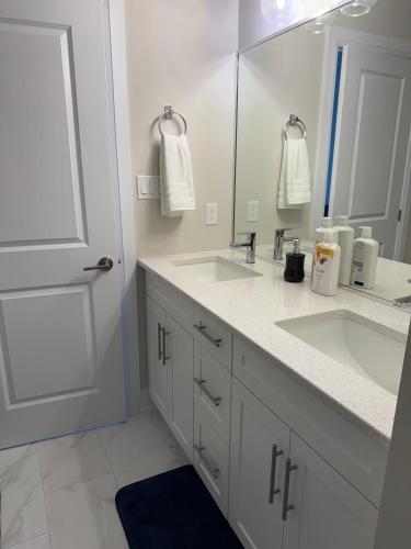 a white bathroom with two sinks and a mirror at Cozy 3 Bedroom Townhome Hyde Park Mall & Western University in London