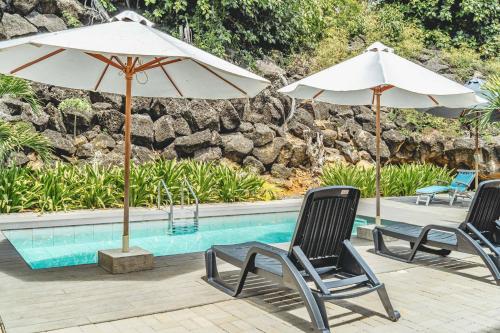 two chairs and umbrellas next to a swimming pool at Ti'Ocean Guest House - Incredible Beachfront Retreat in Grand Gaube