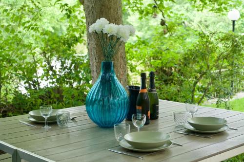 - une table avec un vase bleu, des assiettes et des bouteilles de vin dans l'établissement Au bord de l'eau, à Tendu