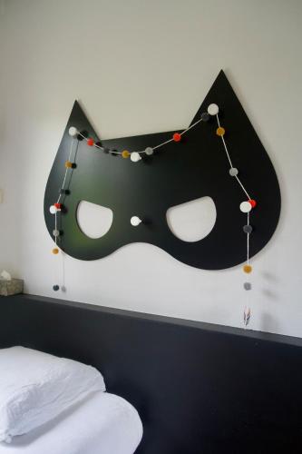 un masque noir suspendu sur un mur à côté d'un lit dans l'établissement Au bord de l'eau, à Tendu