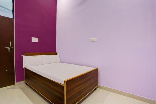 a small bed in a room with a purple wall at Hotel O Chaudhary Hotel in Tatārpur
