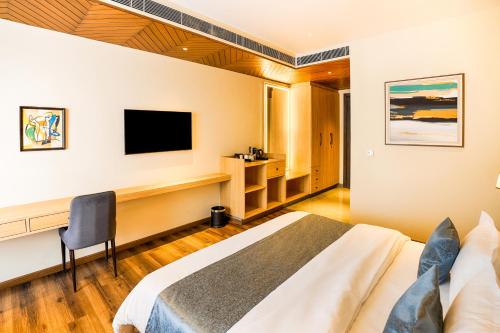 哈尔德瓦尼Hotel Treeline的配有床、书桌和电视的酒店房间