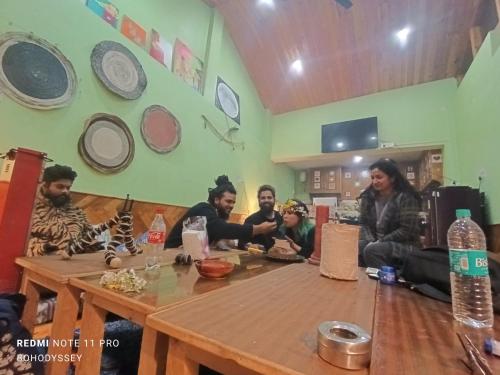 a group of people sitting around a wooden table at BohOdyssey Hallan a Traditional Village Stay with Panoramic Mountain Views in Nagar