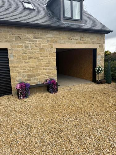 a garage with two purple flowers in front of it at Rural retreat in Longframlington
