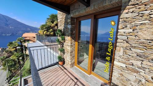 a stone house with a balcony with a view of the water at Sole & Lago-Lake in Maccagno con Pino e Veddasca
