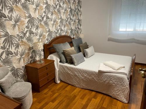 a bedroom with a bed with pillows and a chair at Casa vacacional A de Luisa in Bueu