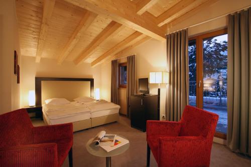a bedroom with a bed and two chairs and a table at Banyan in Sankt Anton am Arlberg