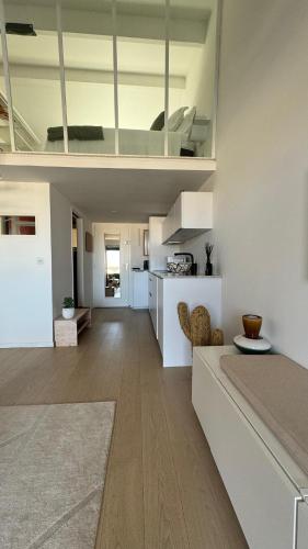 un salon et une cuisine avec des murs blancs et du parquet dans l'établissement Échappée belle à Port-Grimaud Appt 2 personnes, à Grimaud